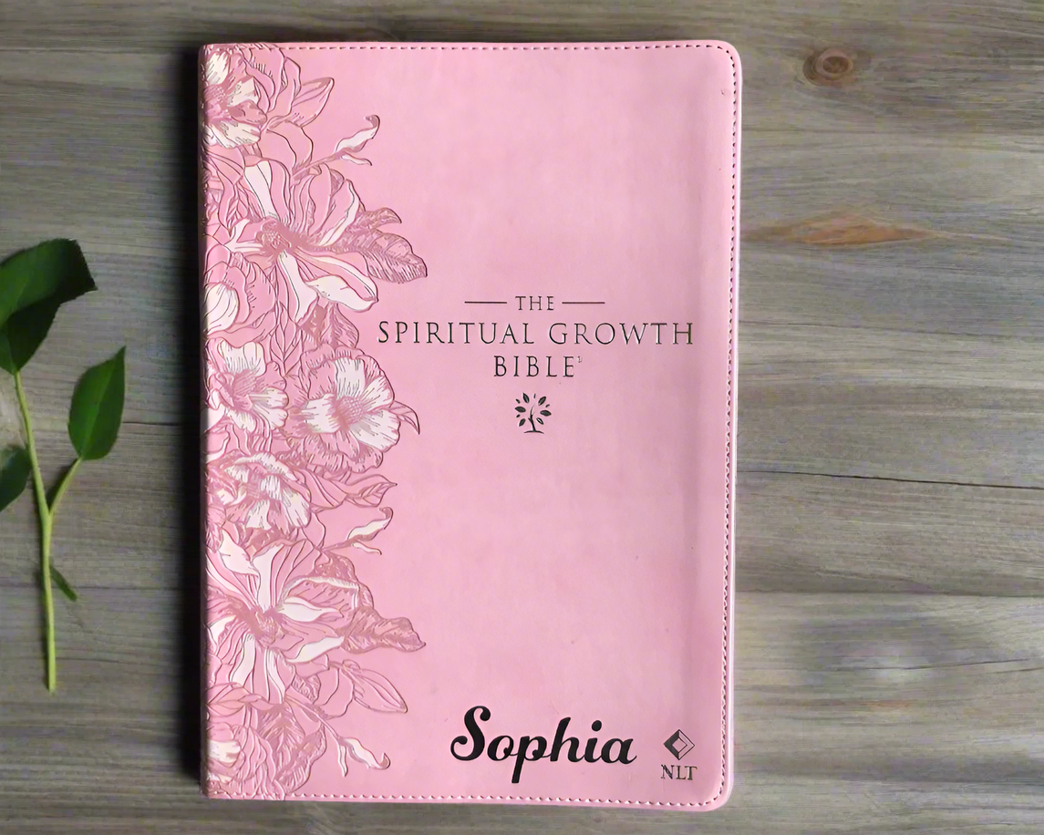 Pink Bible cover with floral design and 'The Spiritual Growth Bible' text on a textured surface.