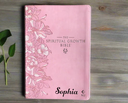 Pink Bible cover with floral design and 'The Spiritual Growth Bible' text on a textured surface.